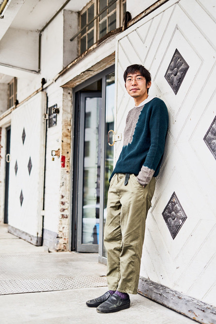 Hiroyuki Murase, founder and designer of the "Suzusan" label, leans against a wall outside of his studio.