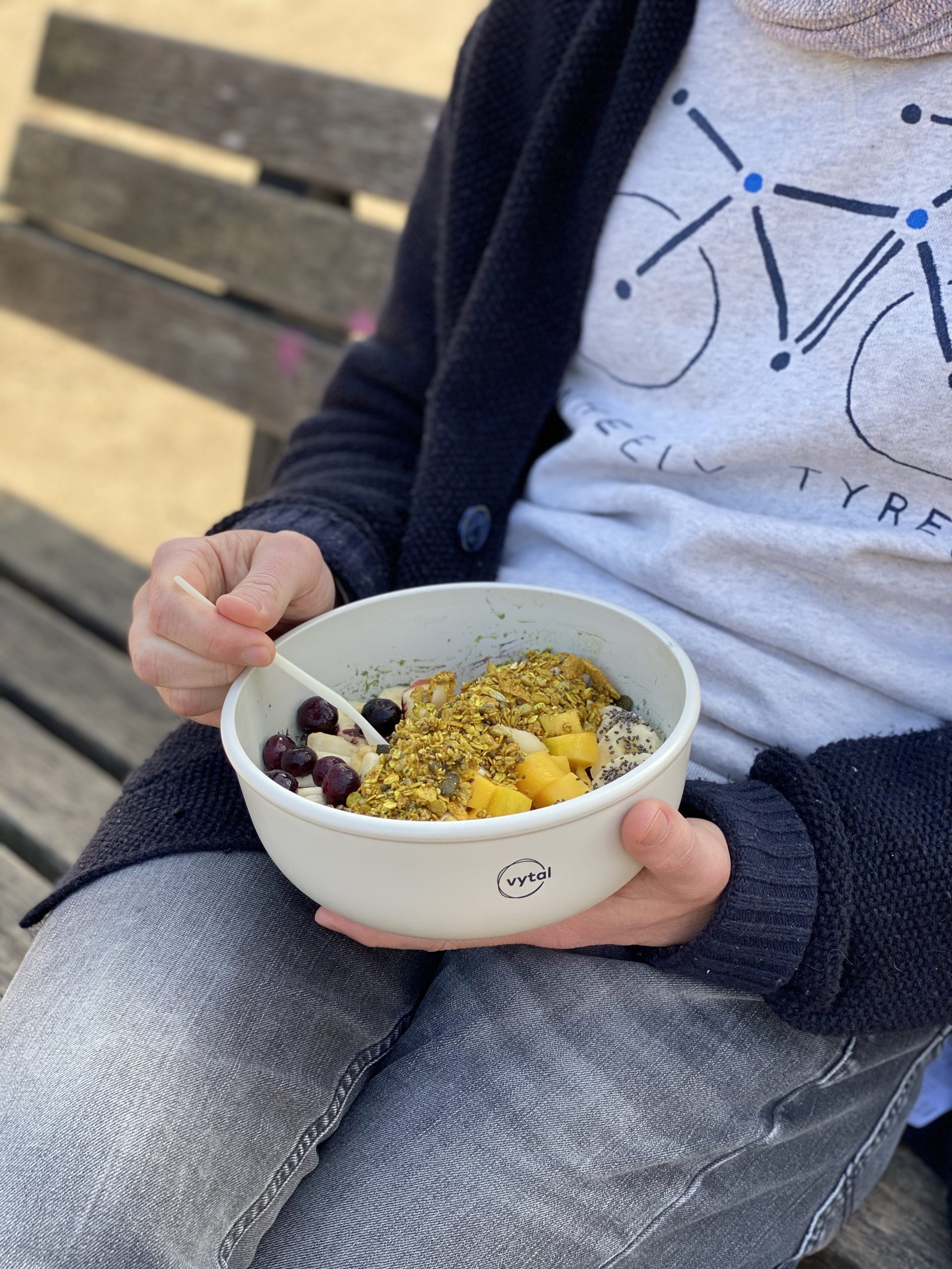 Close up of a VYTAL bowl with cereal and fruit in it that is being held by a person.