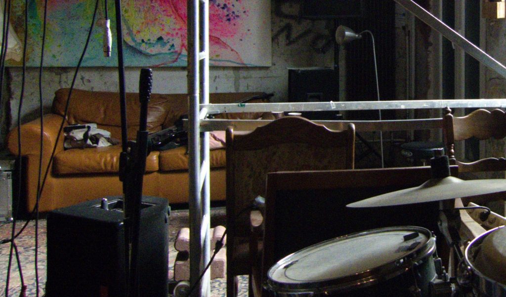 {:gb}Interior of the "Bakery" jazz cellar in Bochum. You can see a drum kit, several chairs, an amplifier, a guitar and a sofa.{:}{:de}Innenbereich des Jazz-Keller "Bakery" in Bochum. Man sieht ein Schlagzeug, mehrere Stühle, einen Verstärker, eine Gitarre und ein Sofa.{:}